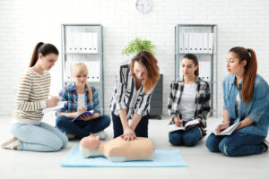 Group of people practicing CPR on mannequin at first aid class