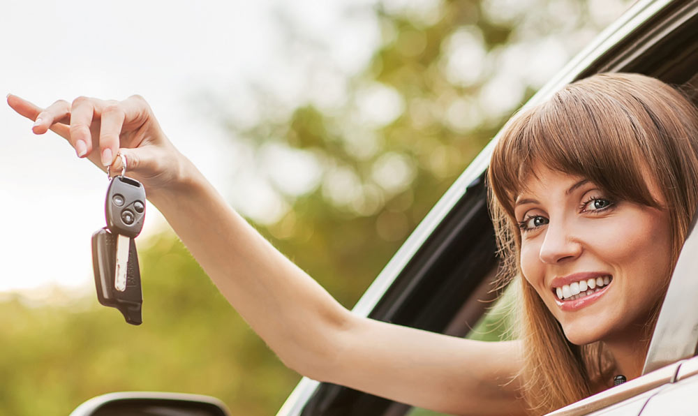 Junge Fahrerin haelt den Autoschluessel aus dem Fenster